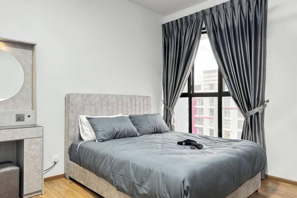 A bedroom with a bed, a dresser, a mirror, and a window with curtains.