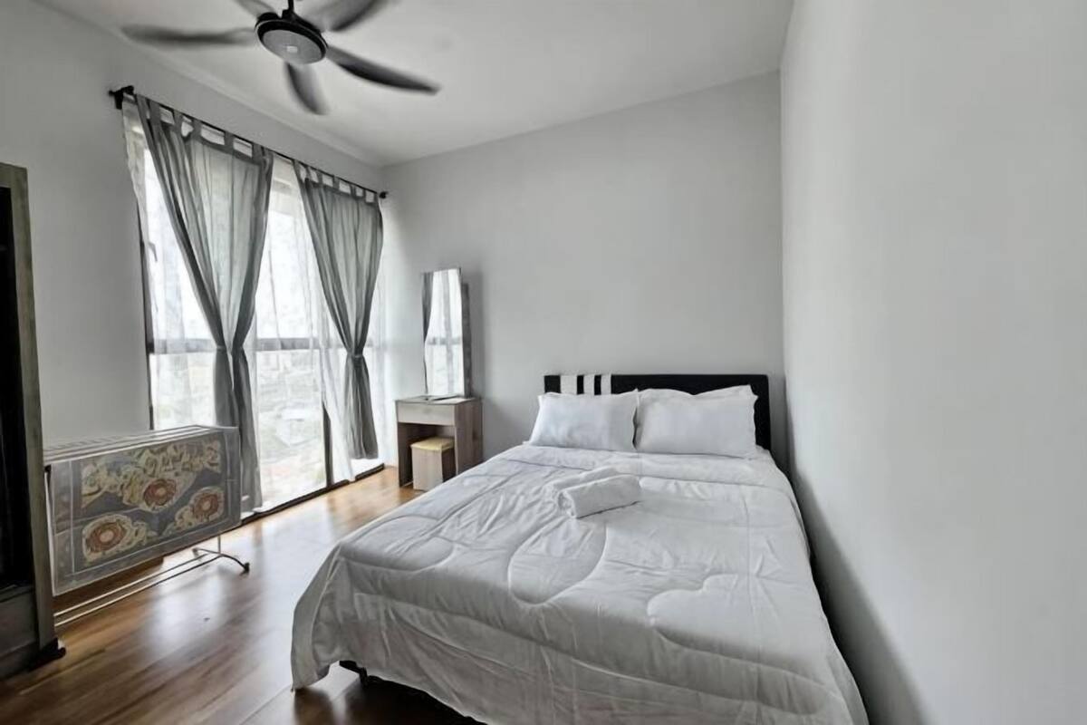 A bedroom with a bed, a ceiling fan, a window with curtains, and a radiator.