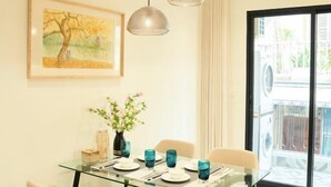 A dining area with a glass table, blue glassware, a vase with flowers, and a framed painting on the wall. - Home by La Sinfonía Trieu Viet Vuong (Hanoi)