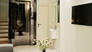 A modern bathroom with a large mirror, a flat-screen TV, and a vase of flowers on the counter. - Home by La Sinfonía Trieu Viet Vuong (Hanoi)