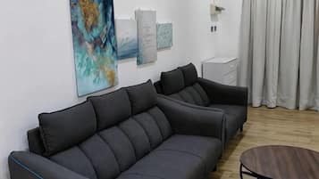 A modern living room with a grey sofa, a round coffee table, and artwork on the wall.