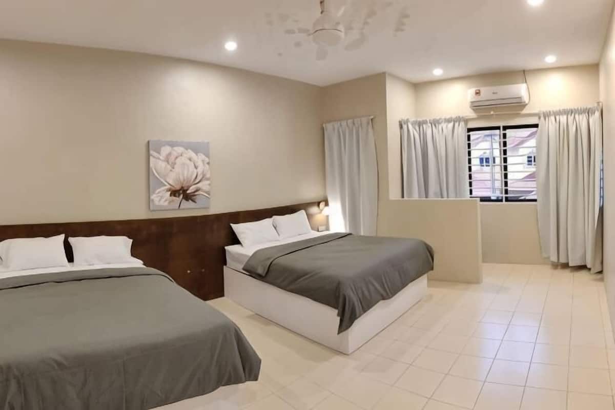 Habitación de hotel con dos camas, un ventanal con cortinas, ventilador de techo y aire acondicionado instalado en la pared.