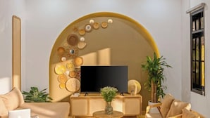 Una sala de estar moderna con un televisor de pantalla plana grande, una mesa de centro redonda y un sofá.