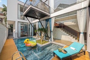Une maison moderne dotée d’une piscine intérieure à panneaux de verre, d’une chaise longue et d’un escalier.