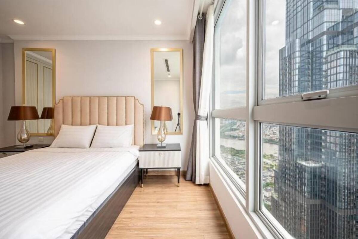 Hotelkamer met een groot bed, bedlampjes, een nachtkastje, een kleintje en een raam met uitzicht op de stad.