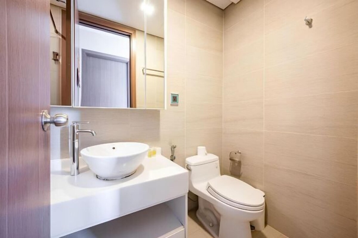 Une salle de bain avec un lavabo blanc, des toilettes et un miroir.