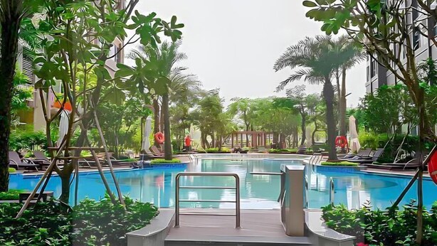 A swimming pool surrounded by lush greenery and palm trees, with steps leading into the water. - Golden Grand Landmark (Ho Chi Minh City)
