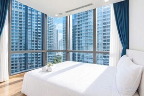 Una habitación de hotel con una cama grande, vistas a edificios altos y una ventana con cortinas.