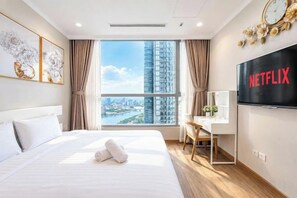 Une chambre d’hôtel avec un grand lit, un bureau, une télévision et une vue sur le paysage urbain.