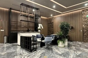 A modern lobby with a marble floor, a reception desk, seating area, and decorative plants. - Golden Grand Landmark (Ho Chi Minh City)