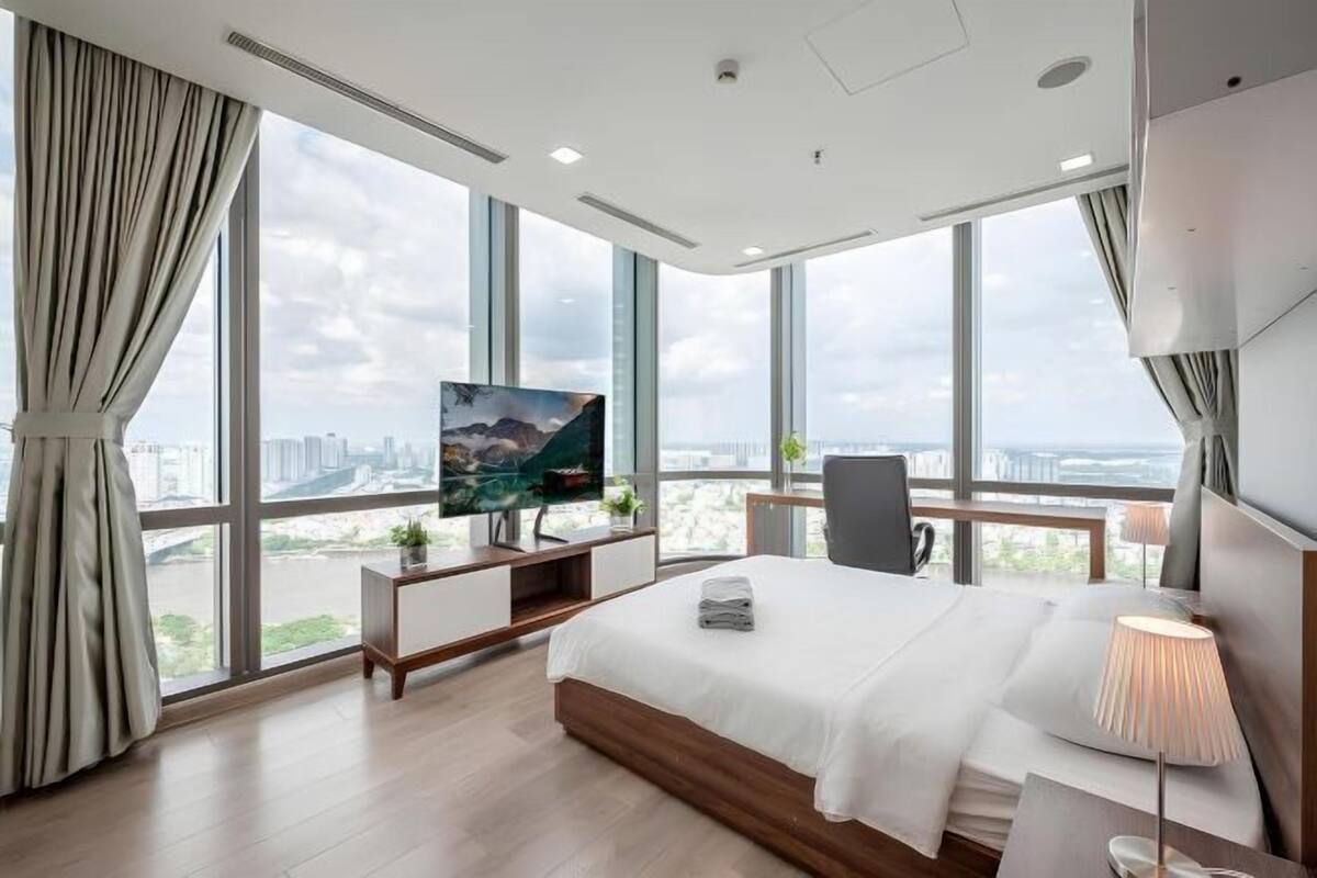 Een moderne hotelkamer met een groot bed, een bureau, een televisie en uitzicht over de stad.