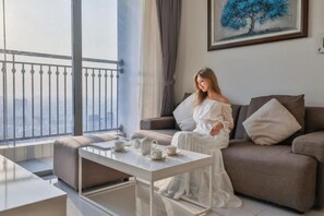 Une femme est assise sur un canapé dans un salon moderne donnant sur un balcon.