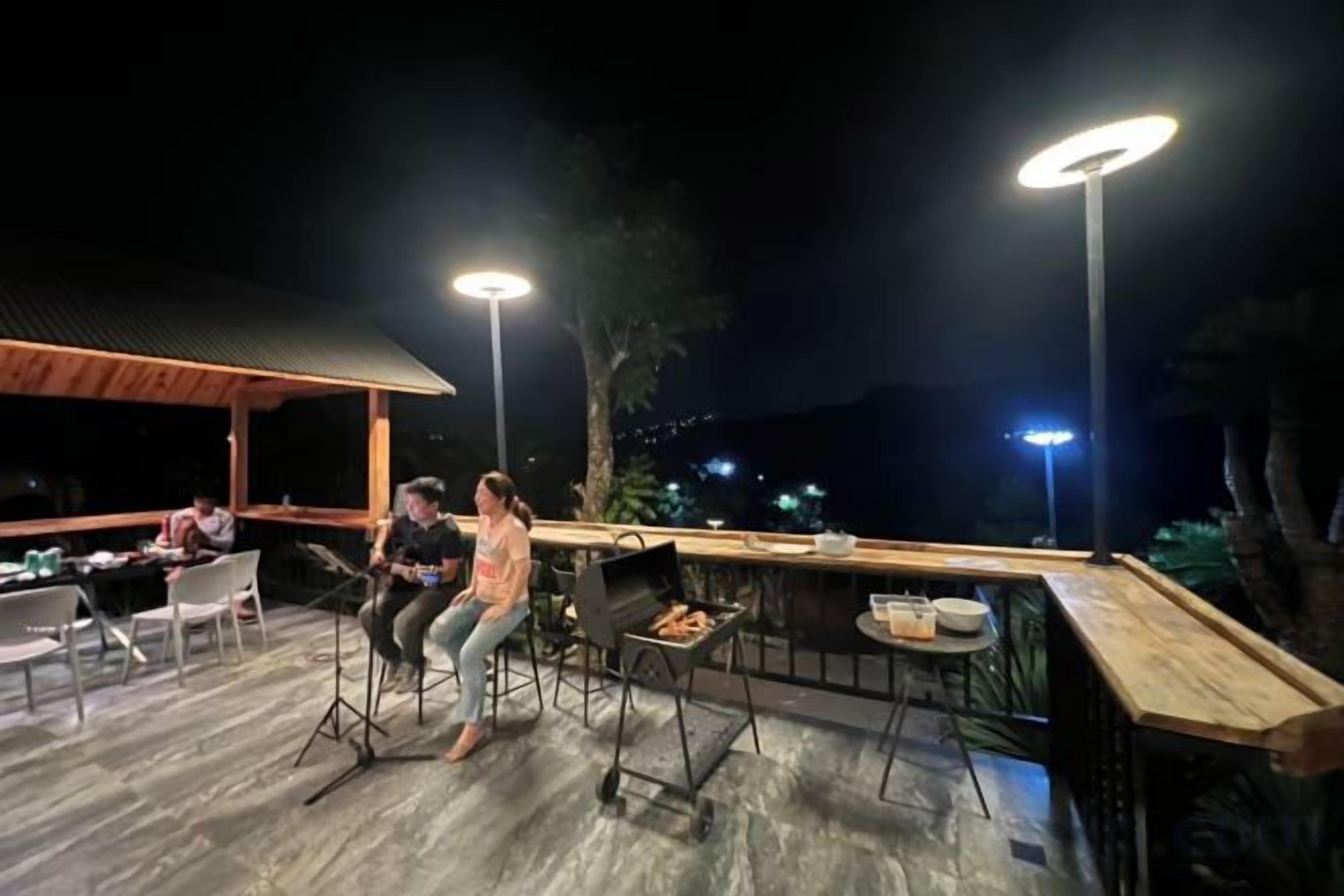Área externa com mesas e cadeiras para refeições, um balcão de bar e uma estrutura de pérgula de madeira.