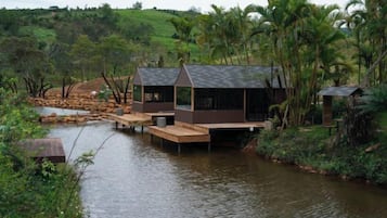 A houseboat with a dock, surrounded by water and greenery.