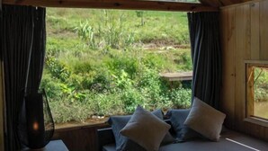 A room with a bed, pillows, a window, and a view of greenery outside. - The Village Resort in the Painting, Bao Loc (Bao Lam District)