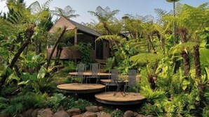 A garden with a dining area, a small building, and lush greenery. - The Village Resort in the Painting, Bao Loc (Bao Lam District)