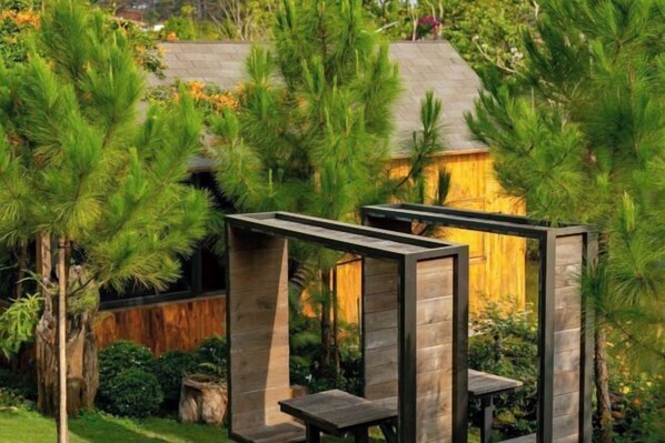 A modern outdoor seating area with wooden structures and lush greenery. - The Village Resort in the Painting, Bao Loc (Bao Lam District)