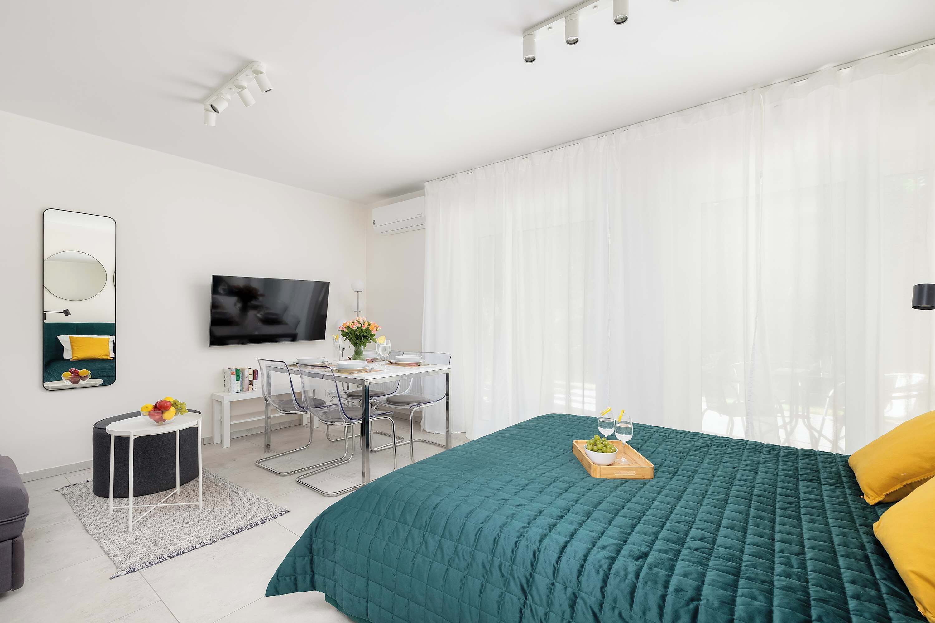 A bright living and sleeping area with a king-size bed and TV. Minimalist design creates a sense of calm.
