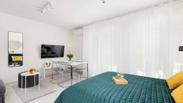 A bright living and sleeping area with a king-size bed and TV. Minimalist design creates a sense of calm.