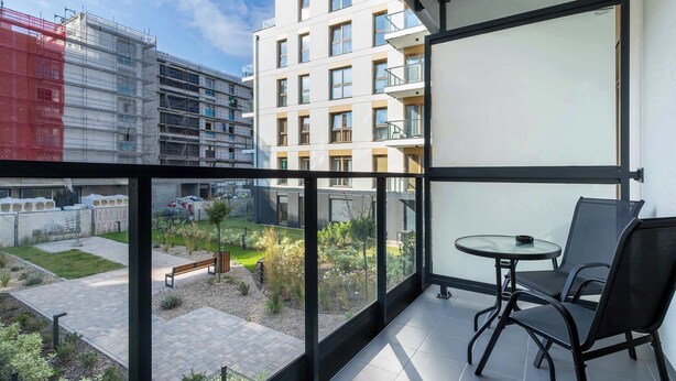 Uma varanda com vista para um jardim e um edifício em construção.