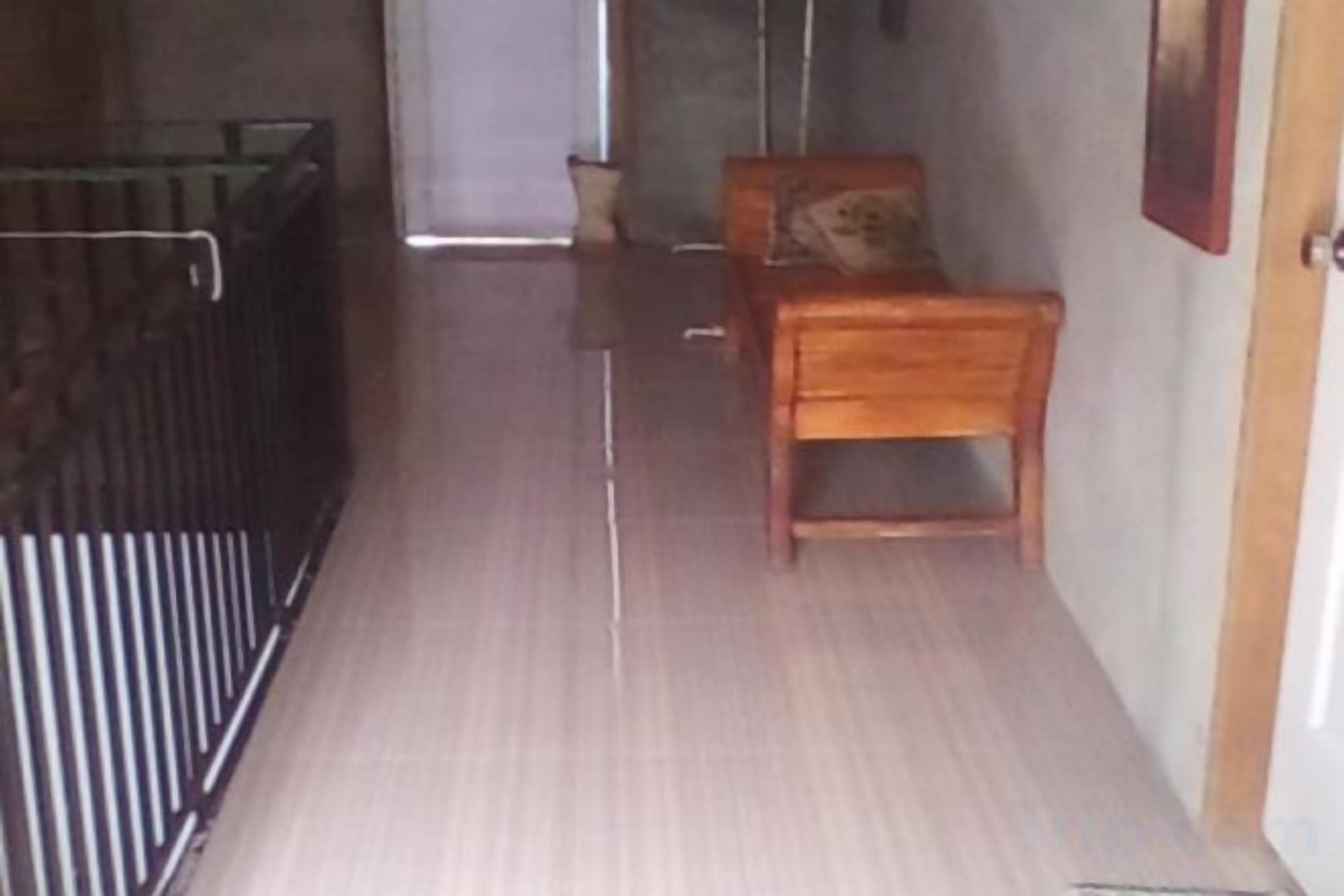Un pasillo estrecho con un banco de madera y una cuna de metal.