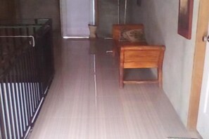 Un pasillo estrecho con un banco de madera y una cuna de metal.