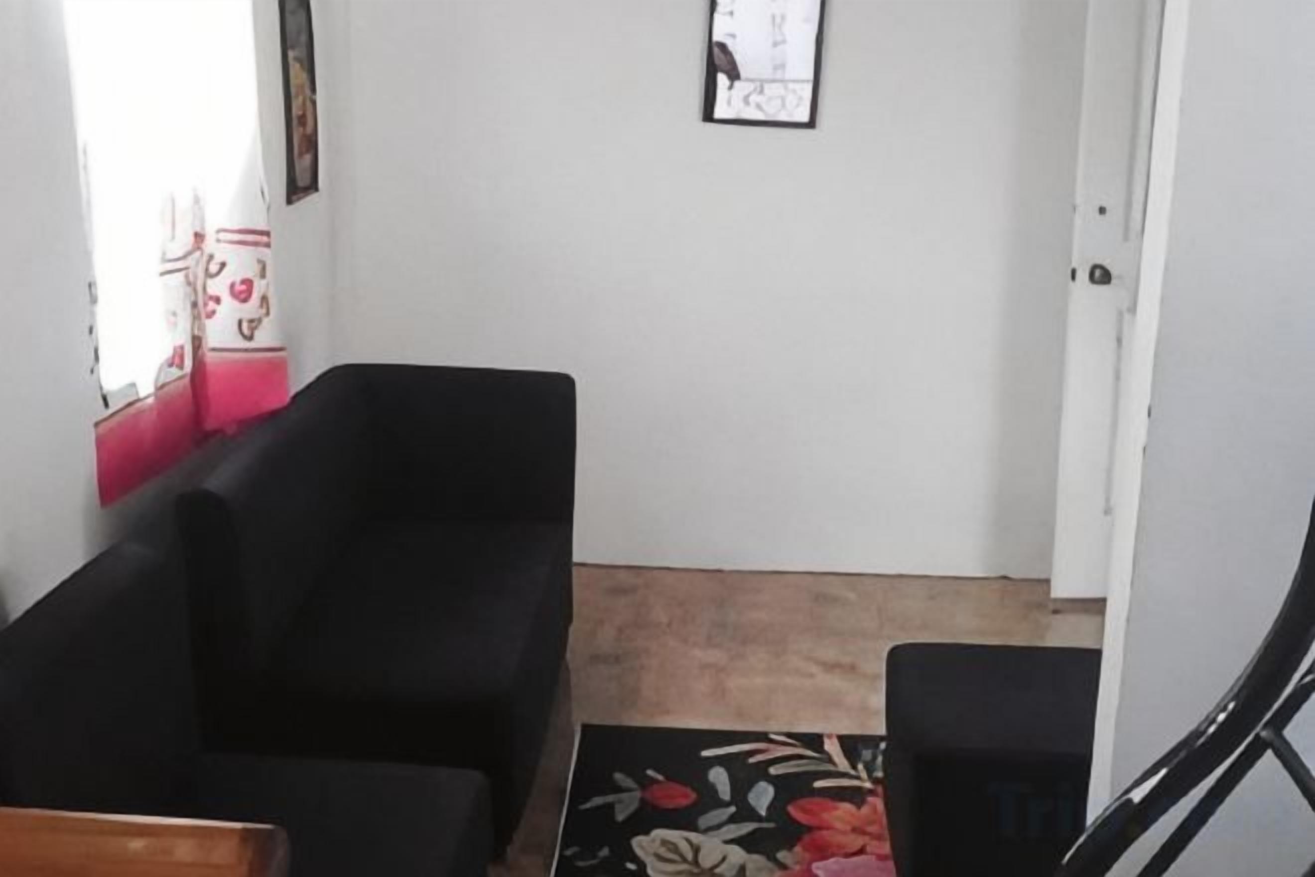 A living room with a black sofa, a small table, and a patterned rug.