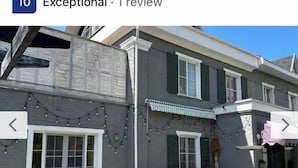 A two-story house with a grey exterior, white trim, and green shutters. There are string lights hanging on the exterior wall. - Fotofabrika - Unique Beautiful 3 Storeys House (Oskemen)