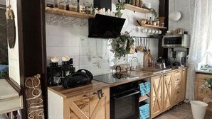A modern kitchen with wooden cabinets, a built-in oven, a microwave, and various kitchen appliances. - Fotofabrika - Unique Beautiful 3 Storeys House (Oskemen)
