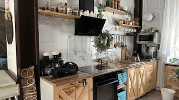 Een keuken met houten kastjes, een magnetron, een koffiezetapparaat en diverse keukengerei.