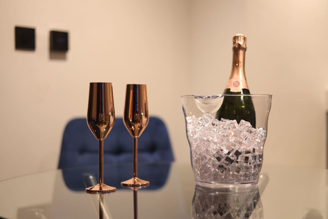 Two champagne flutes on a table with a bottle of champagne in a crystal ice bucket.