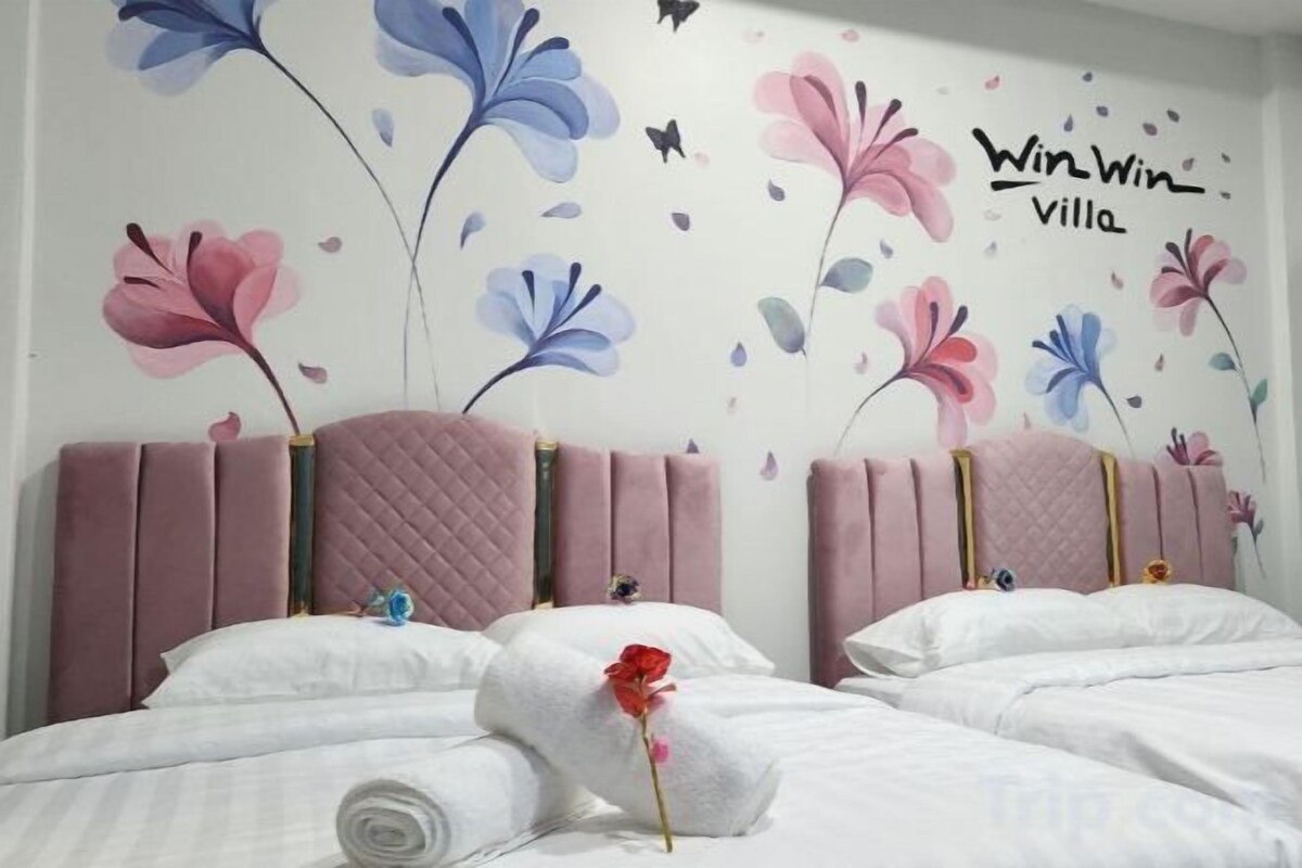 Une chambre d’hôtel avec un lit, des oreillers et un mur décoré de motifs floraux.