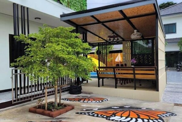 A covered outdoor seating area with a tree and patterned ground design. - Win Win Villa (Sattahip)