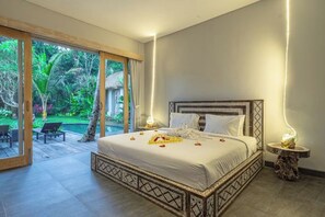 Un dormitorio amplio con una cama grande, vistas a un jardín exuberante y una piscina exterior.