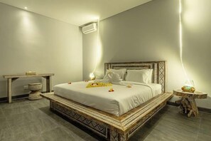 Un dormitorio con cama, mesitas de noche y aire acondicionado de pared.