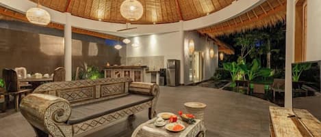 A spacious lobby with a high ceiling, a sofa set, a dining table, and a bar area.