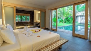 Un dormitorio amplio con una cama grande, chimenea empotrada y vistas a una piscina.