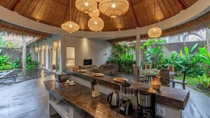 Una cocina moderna con una isla curva, electrodomésticos integrados y techo de paja.