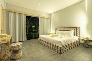 Un dormitorio con una cama grande, una mesita de noche, una mesa redonda y vistas al exterior.