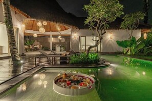 A pool area with a dining setup, lounge chairs, and a thatched-roof structure. - Brand New luxury 3BR Villa Ethnic Ubud #2 (Bali)