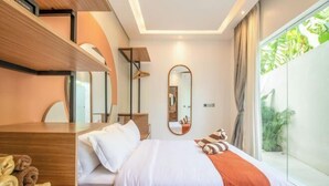 Een moderne hotelkamer met een groot bed, een houten bureau, een spiegel en uitzicht op groen.