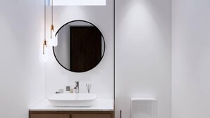 Een moderne badkamer met een ronde spiegel, een wit wastafelmeubel en een toilet.
