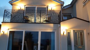 Een woonhuis met twee verdiepingen, een balkon, grote ramen en een deur.