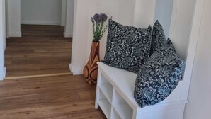 Ein Flur mit einer weißen Bank, einem Spiegel und einer Vase mit Blumen.