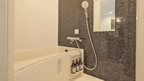 A bathroom with a bathtub, a shower, a mirror, and a wall-mounted control panel. - Fandina Tokyo (Tokyo)