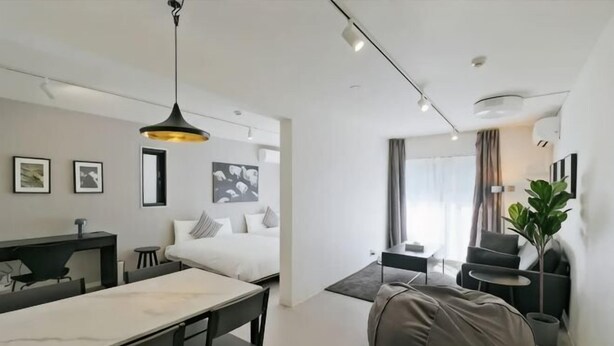 A modern hotel room with a dining area, a bed with pillows, a large bean bag, a potted plant, and a view of the outside. - Fandina Tokyo (Tokyo)