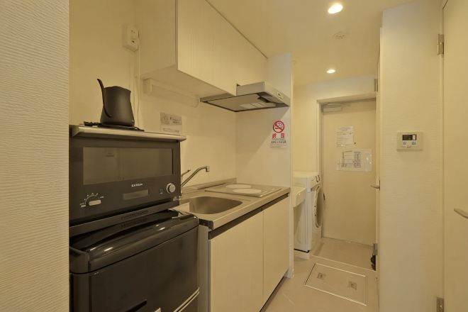 A compact kitchen with a microwave, stove, and sink.
