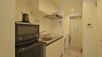 A compact kitchen with a microwave, stove, and sink.