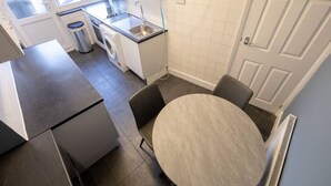 Een praktische keuken met een spoelbak, wasmachine en een eethoek met een tafel en stoelen.