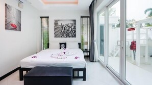 Ein modernes Hotelzimmer mit einem großen Bett, einer Bank, einer Deckenleuchte, einem Fenster mit Jalousien und Blick ins Freie.